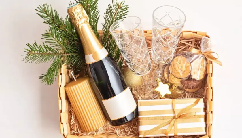 Festliche Fresskorb Ideen: Sektflasche, Gläser, Kerze, Kekse und Geschenk.
