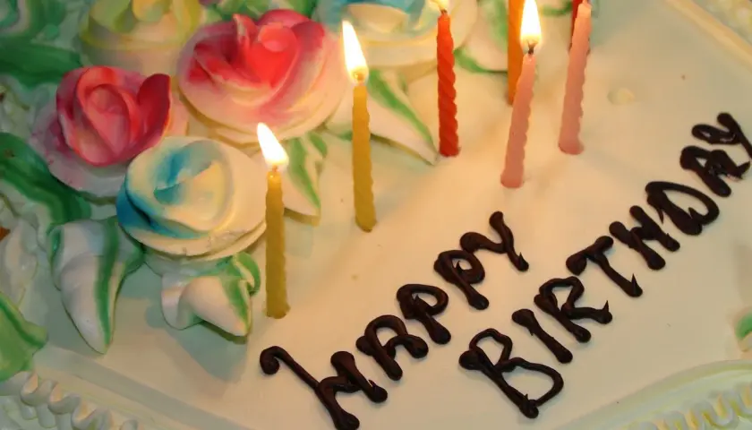 Pastel de cumpleaños con rosas de crema y velas encendidas. ¡Espero que estos textos de cumpleaños para mi novio largas hagan llorar de emoción!