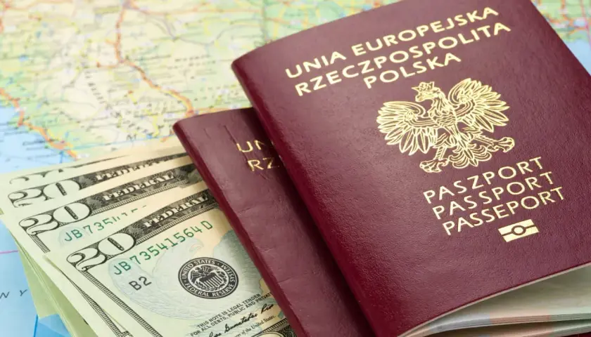 Dwa polskie paszporty i stos banknotów dolarowych na tle mapy. Czy do Rumunii potrzebny jest paszport? Sprawdź przed podróżą!