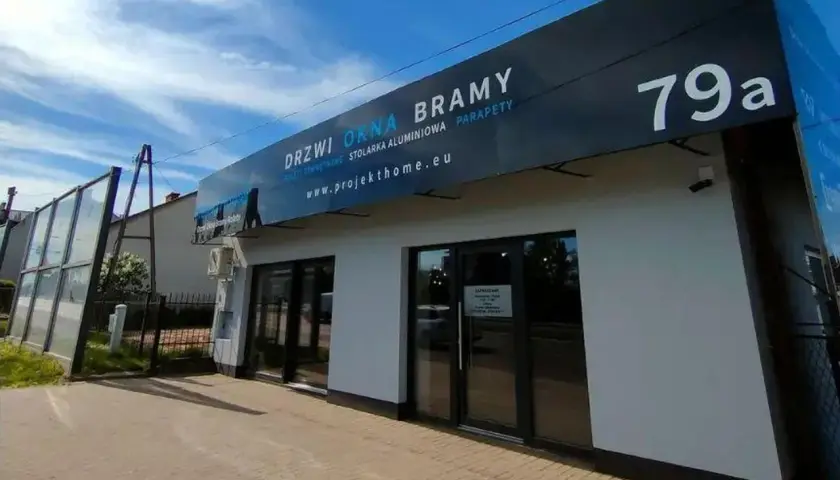 Nowoczesny salon okien i drzwi z szyldem "DRZWI OKNA BRAMY" i numerem 79a.
