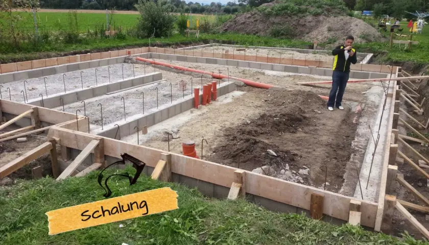 Baufortschritt: Die **Schalung** für das Fundament ist vorbereitet, Bewehrungsstahl und Rohre liegen bereit.