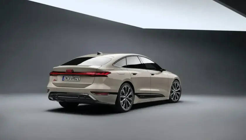 Elegancki tył nowego Audi A6 2025 w kolorze piaskowym, z charakterystycznym pasem świateł LED i sportowymi felgami.
