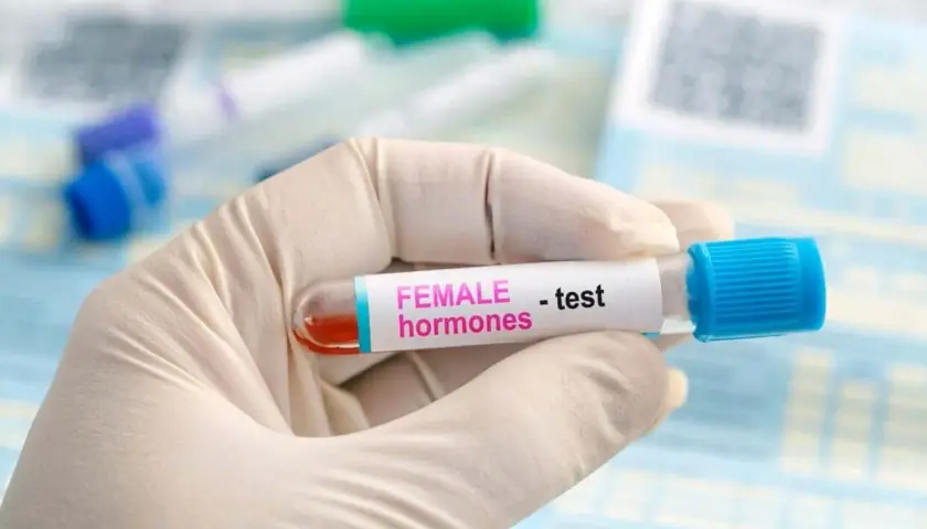 Rękawiczka medyczna trzyma probówkę z krwią do badania poziomu hormonów, w tym FSH.