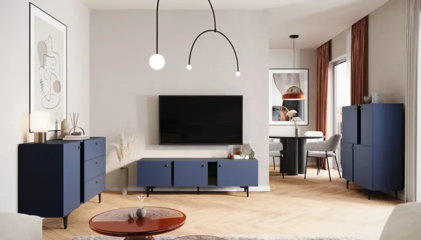 Nowoczesny salon z granatowymi meblami i ekstrawagancką lampą. W tle stół z krzesłami.