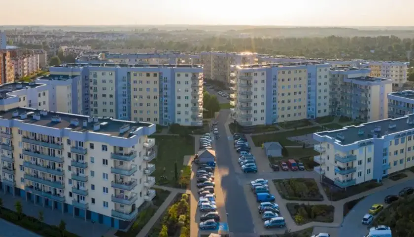 Widok z lotu ptaka na osiedle bloków mieszkalnych z balkonami i parkingami.