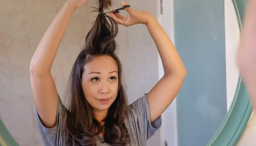 Mujer se corta el pelo en casa, creando un corte de pelo a capas.