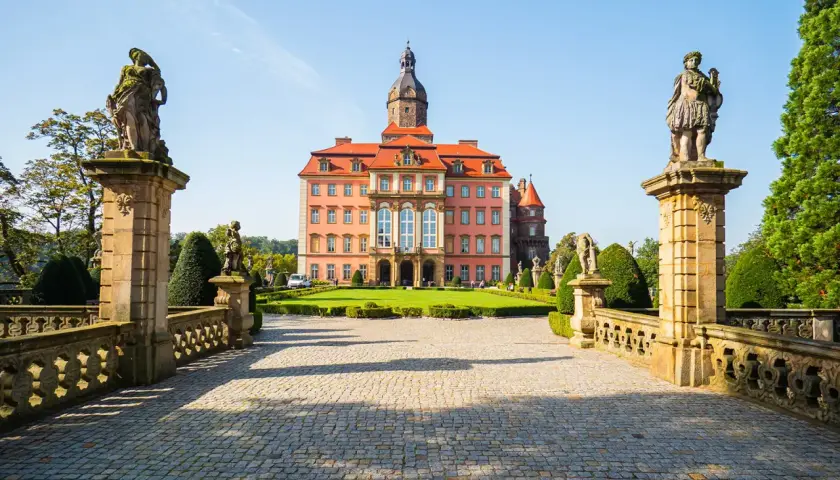 Zamek Książ z różową fasadą i wieżą, otoczony ogrodem. Poznaj zamek Książ ciekawostki i jego tajemnice.