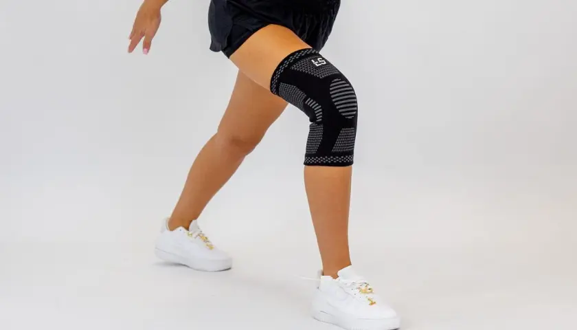 Czarny stabilizator na udo z szarymi wzorami, noszony przez kobietę podczas ćwiczeń.