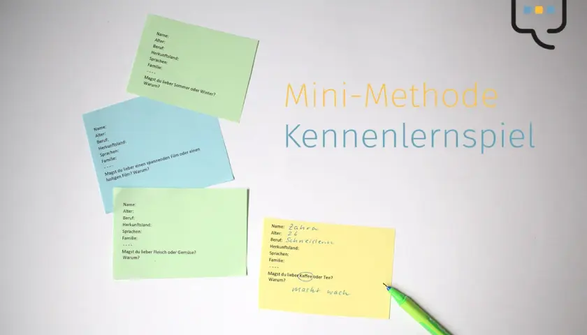 Bunte Zettel mit Fragen für ein Kennenlernspiel liegen auf weißem Grund. Ein grüner Stift liegt daneben.