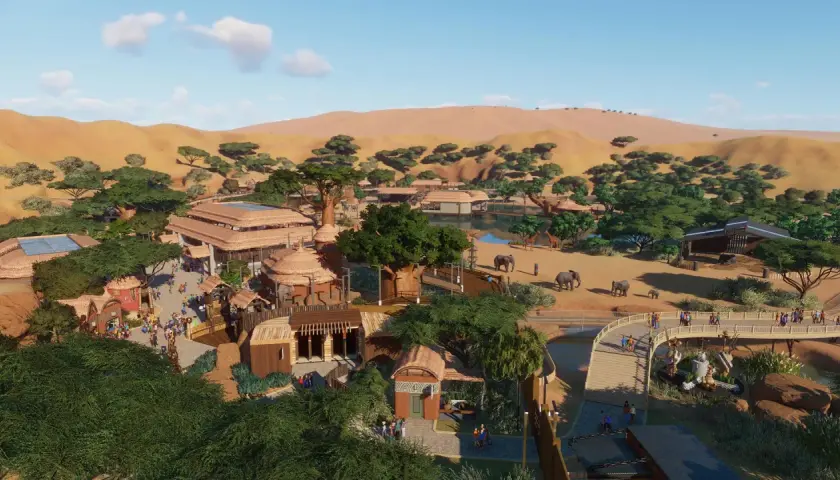 Vue aérienne d'un zoo inspiré de l'Afrique, avec des éléphants, des girafes, des bâtiments aux toits de chaume et des dunes en arrière-plan. Un exemple de configuration Planet Zoo.