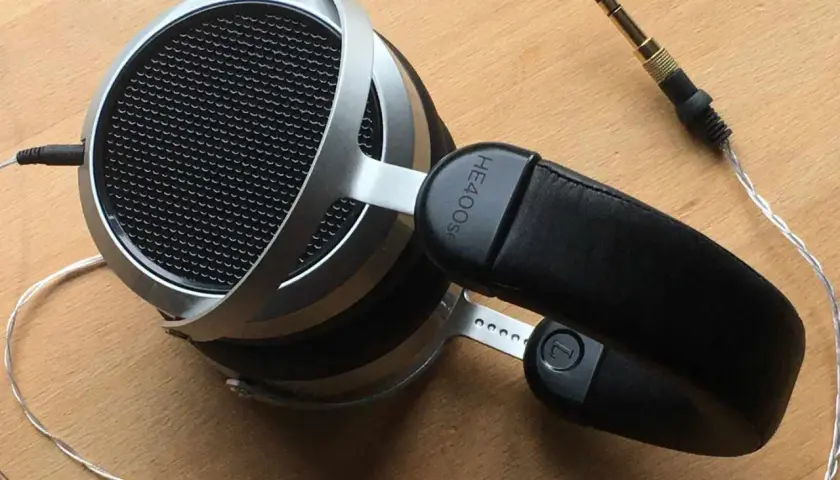 Hifiman HE400SE Test: Offene Kopfhörer mit silbernem Bügel und schwarzem Leder-Kopfband. Der 3,5mm Klinkenstecker liegt daneben.