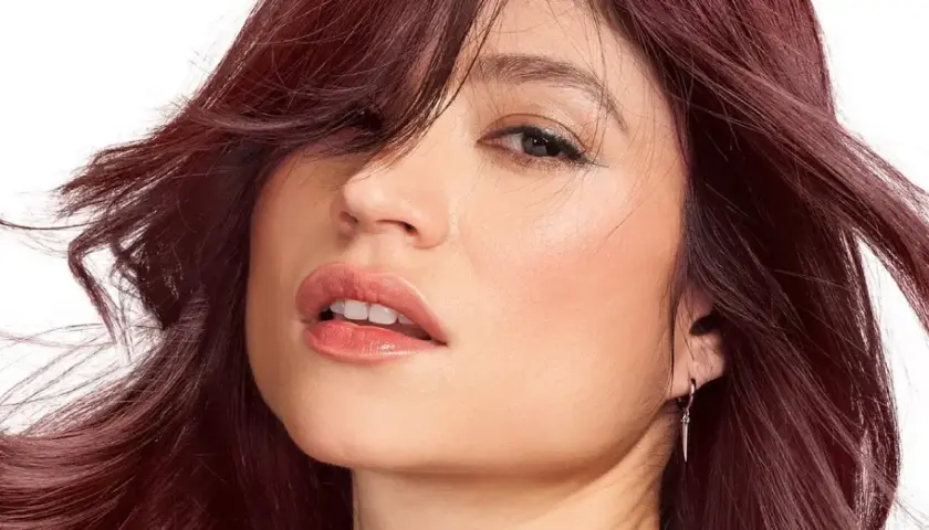 Mujer con un vibrante **cherry pelo** que enmarca su rostro, con labios jugosos y una mirada cautivadora.