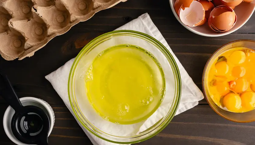 Préparation pour une recette : blancs d'œufs dans un bol, jaunes d'œufs dans un autre, et coquilles dans une coupelle. Le tout prêt à être mis au frigo.