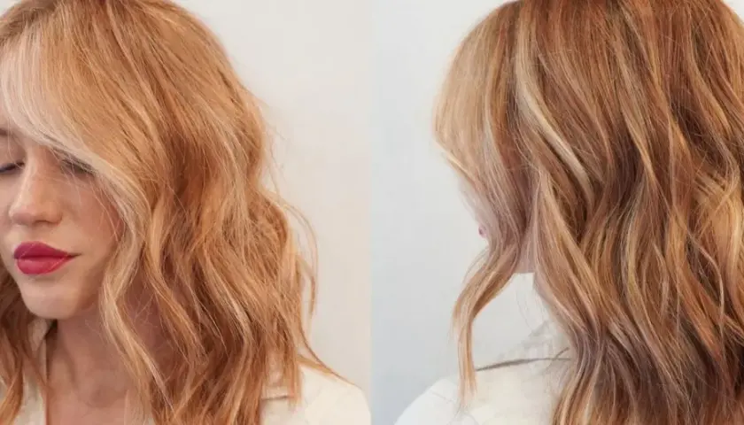 Mujer con cabello ondulado rubio fresa con reflejos dorados y rosados.