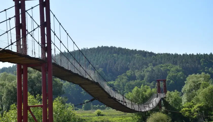 Drewniany most wiszący, najdłuższy w Polsce, wije się nad zieloną doliną.