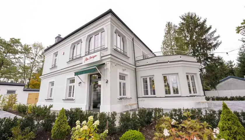 Elegancka willa z napisem "La Maison" Michel Moran. Piękny ogród przed budynkiem.
