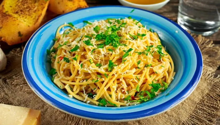 Aglio olio z parmezanem i natką pietruszki, podane z grzankami czosnkowymi.