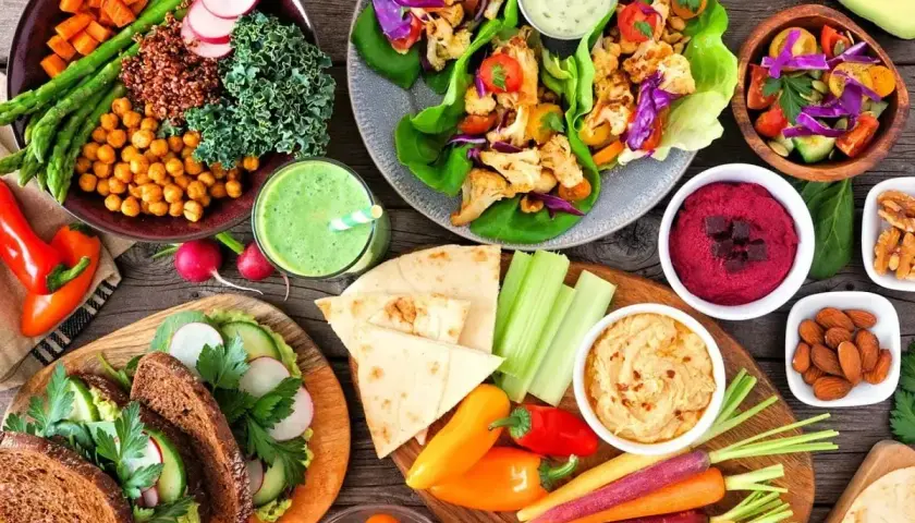 Kolorowe, wegańskie potrawy: sałatki, wrapy, hummus, smoothie i pieczywo. To pokazuje, co to jest weganizm – dieta roślinna pełna smaków i zdrowia.