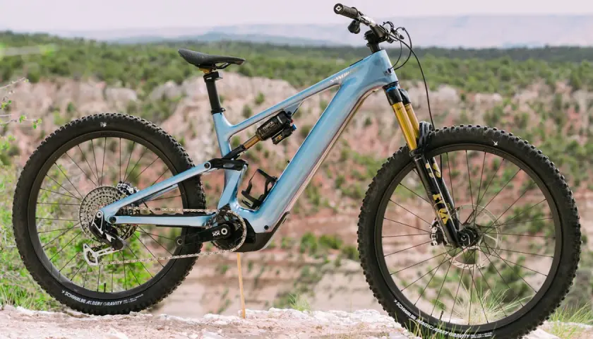 A light blue specialized levo 4 electric mountain bike is parked on a rocky trail with a scenic canyon in the background.