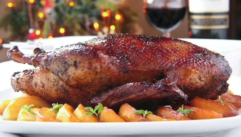 Pieczona kaczka z chrupiącą skórką, podana z jabłkami i ziołami.