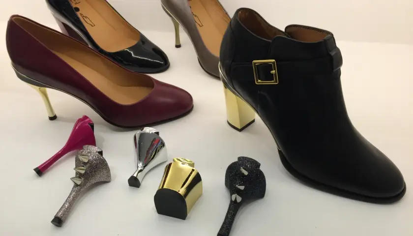 Buty z wymiennymi obcasami: czarne botki, bordowe i czarne szpilki, szare czółenka oraz ozdobne obcasy.
