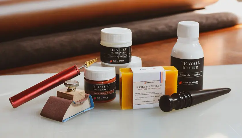 Outils pour travailler le cuir : teinture, cire d'abeille, résine de finition et un bloc pour poncer du cuir.