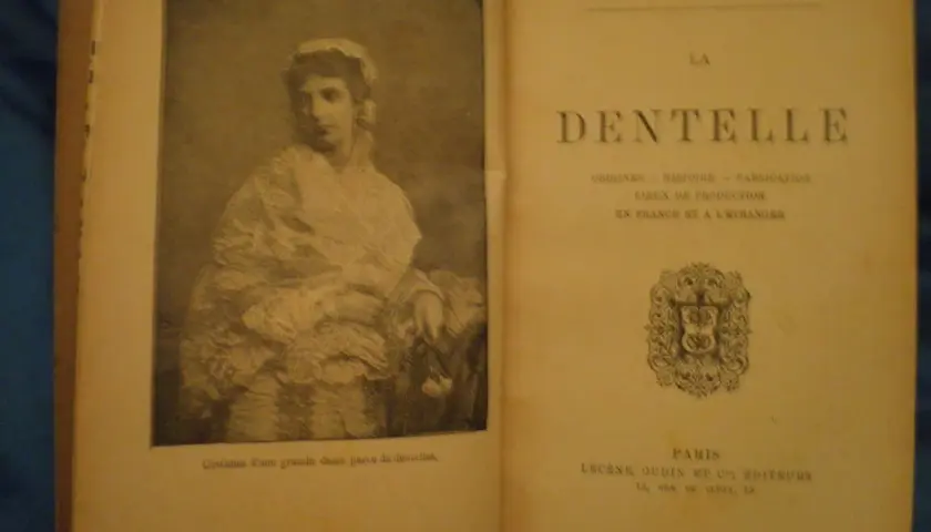 Livre sur la dentelle, avec une gravure de dame en costume orné de dentelles. Le texte évoque l'histoire de la dentelle.