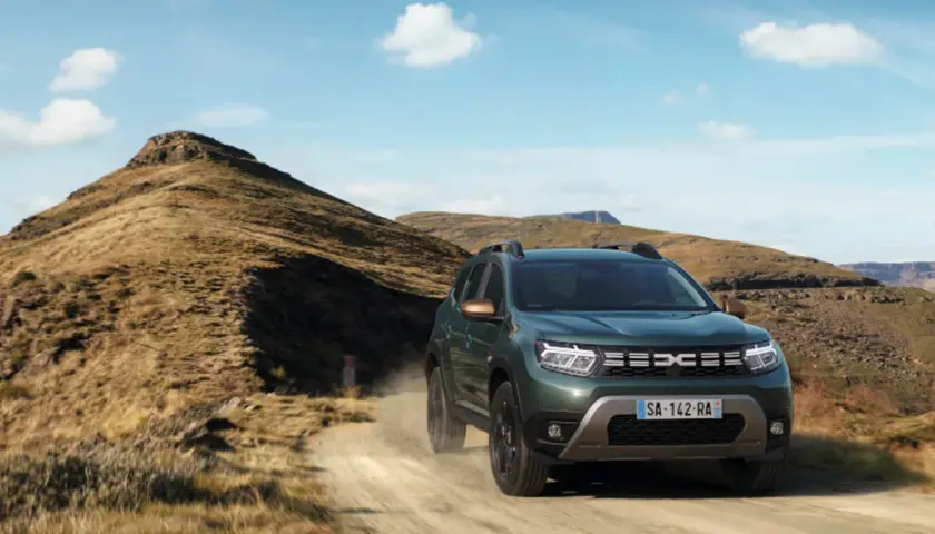 Zielony Dacia Duster off road pokonuje piaszczystą drogę wśród skalistych wzgórz.
