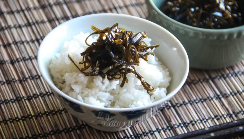 A bowl of white rice topped with dark, glistening tsukudani, a savory seaweed dish. This image hints at a delicious tsukudani recipe.