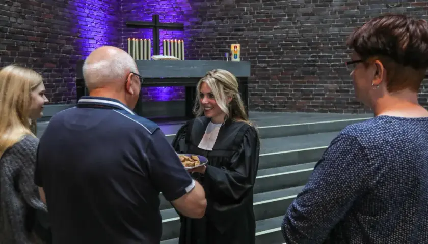 Frauen in der kirche: Eine Geistliche teilt Brot mit Gemeindemitgliedern.