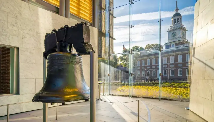 Liberty Bell w nowoczesnym wnętrzu, z widokiem na Independence Hall i kwitnące kwiaty.
