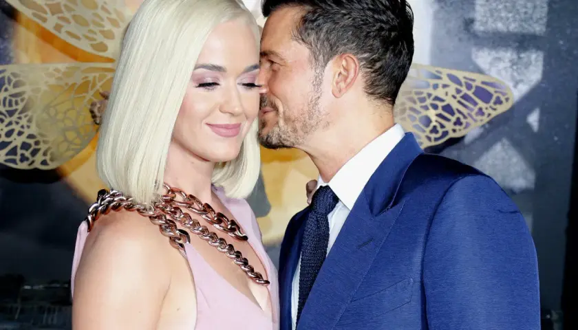 Katy Perry i Orlando Bloom w czułym uścisku. Ona w różowej sukni i masywnym naszyjniku, on w granatowym garniturze.