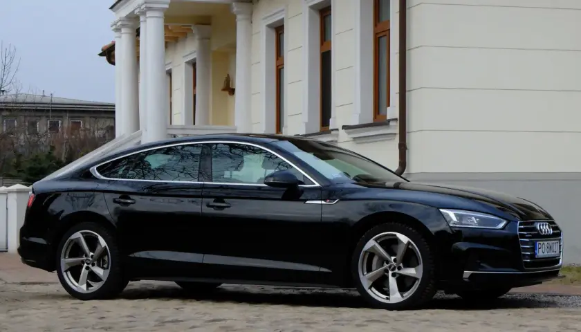 Eleganckie, czarne Audi A5 z 2018 roku zaparkowane przed klasycznym budynkiem z kolumnami.