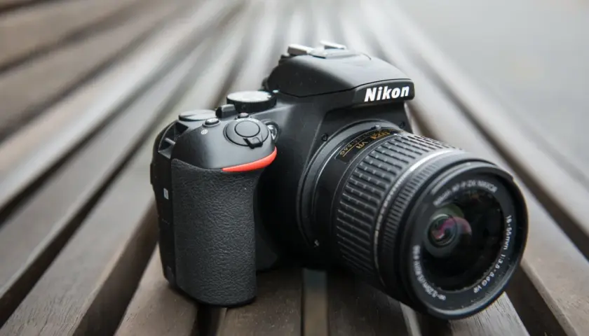 Czarny aparat Nikon D3300 z obiektywem na drewnianym tle.