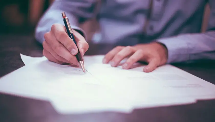 Ręka pisze na papierze, wypełniając dokumenty dotyczące podatku od spadku po wujku.