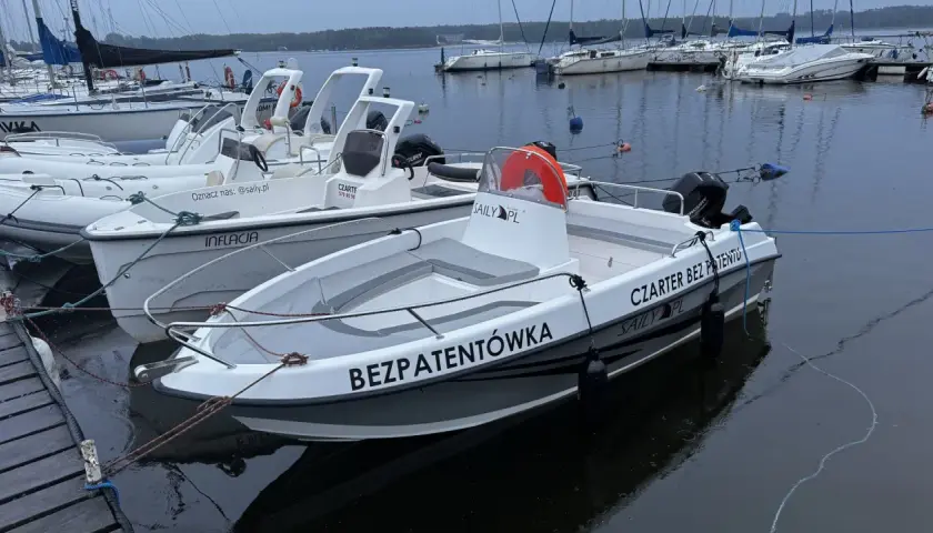 Łodzie motorowe cumujące przy pomoście, gotowe na czarter na Zalewie Sulejowskim. Jedna z nich ma napis "BEZPATENTÓWKA".