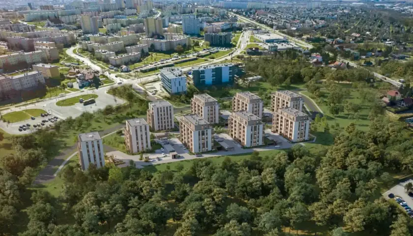 Nowe inwestycje w Kielcach: nowoczesne bloki mieszkalne otoczone zielenią, w tle widoczne osiedla i droga.
