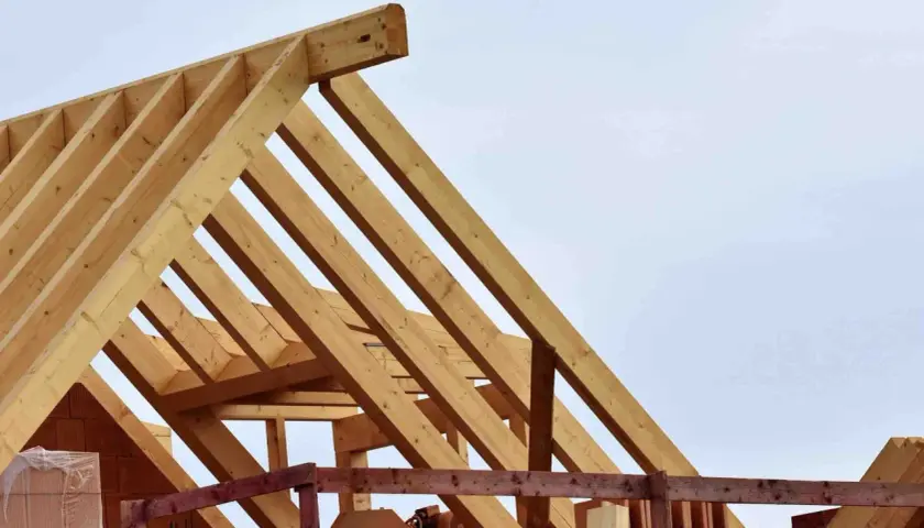 Holzkonstruktion für den dachstuhl aufbau. Balken bilden ein stabiles Gerüst gegen den hellblauen Himmel.