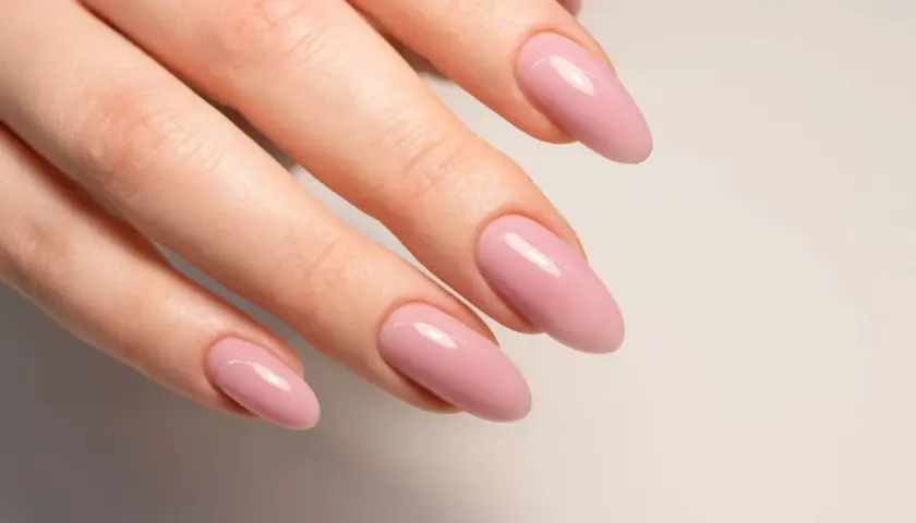 Manicura con uñas semipermanentes naturales en tono rosa pálido, con forma almendrada y acabado brillante.