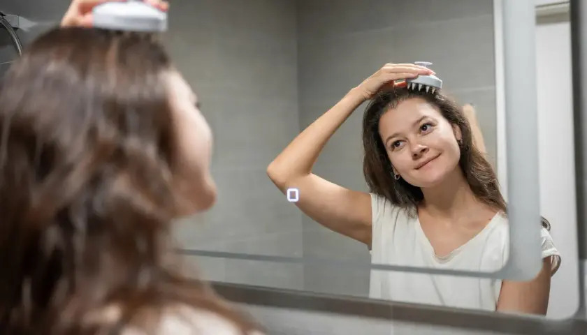 En kvinna njuter av en avkopplande scalp massage framför en spegel.