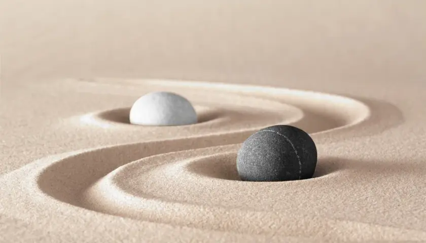 Due pietre, una bianca e una grigia, su sabbia rastrellata, evocano le yin e yang caratteristiche di equilibrio e dualità.