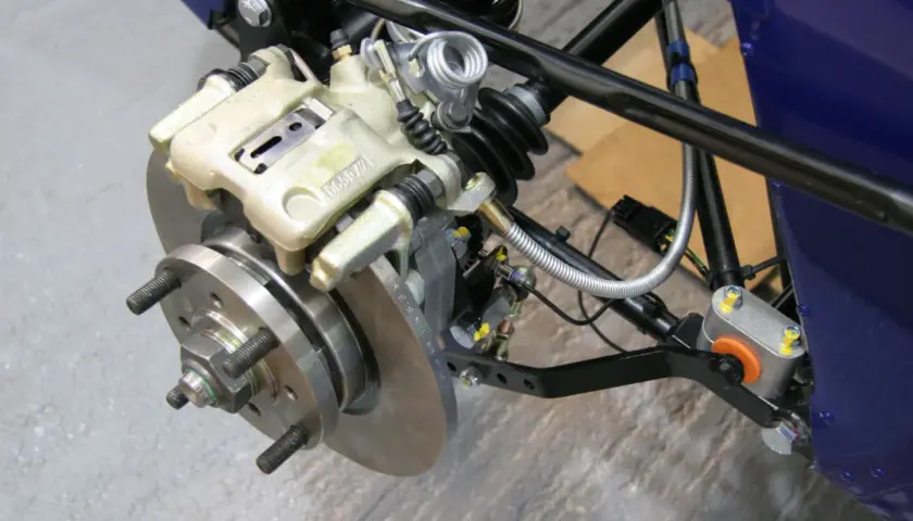 Dettaglio del sistema frenante di un veicolo, con pinza, disco e componenti di sospensione. Pronto per lo spurgo freni scooter.