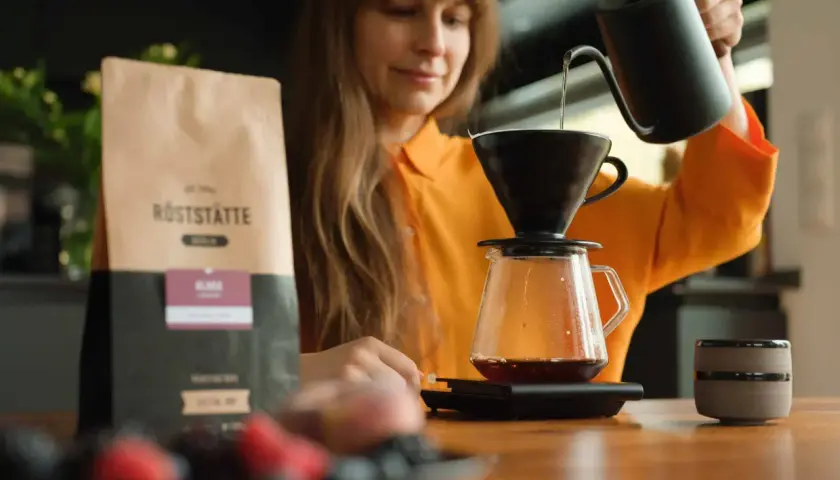 Frau brüht Kaffee. Informationen über Kaffee in der Schwangerschaft folgen.