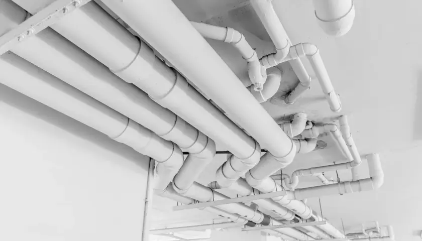Skomplikowany system białych rur pehd biegnie pod sufitem, tworząc labirynt instalacji.