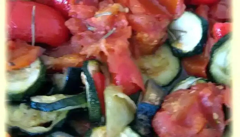 Un plat coloré de ratatouille au four, avec des rondelles de courgettes, des poivrons rouges et des tomates. Un délice provençal !