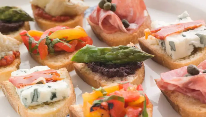 Variedad de crostini italiano: con salami, queso azul, espárragos, tomates y aceitunas.