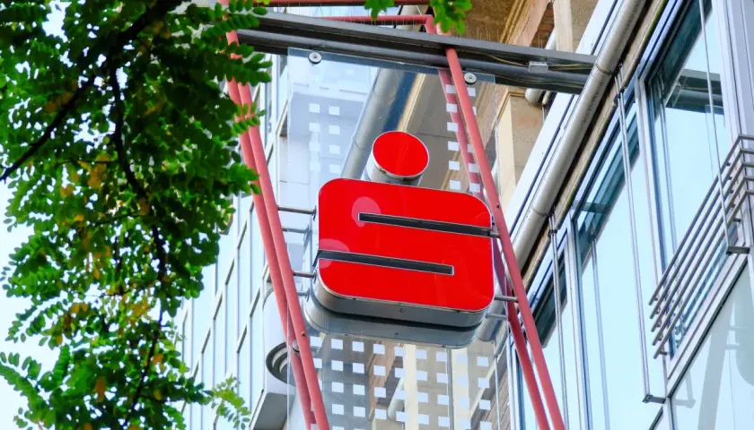 Rotes Sparkassen-Logo an einem Gebäude. Die Frage "wie lange bucht die Sparkasse" wird hier nicht beantwortet, aber das Logo ist gut sichtbar.