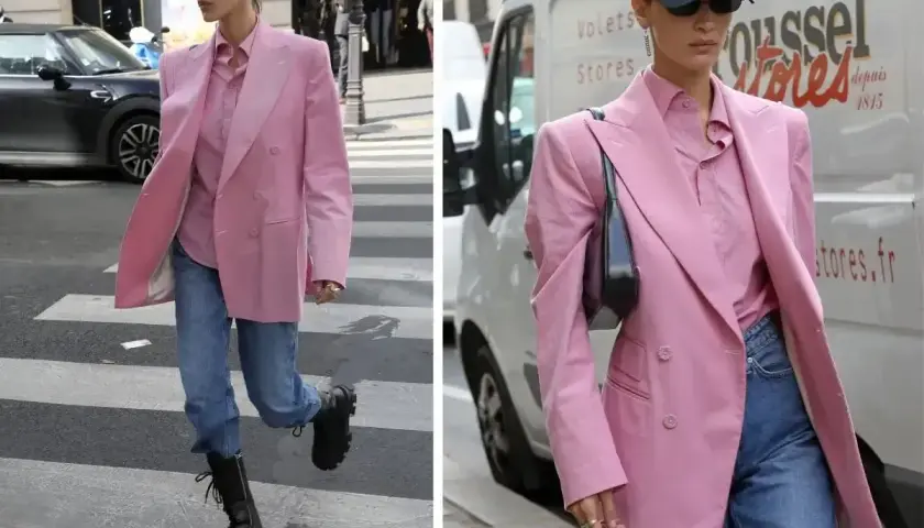 Kobieta w marynarce w odcieniu **magenta kolor** i jeansach idzie ulicą.