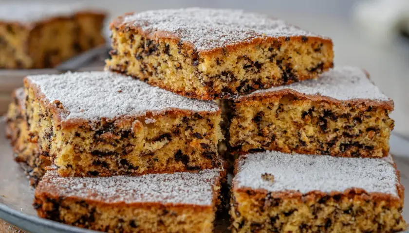 Stapel von saftigen Kuchenstücken mit Schokostückchen, bestäubt mit Puderzucker. Perfekt für einen schnellen Kuchengenuss.