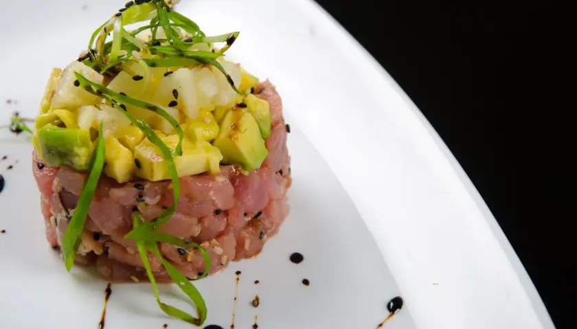 Deliziosa tartare di tonno con avocado e ananas, guarnita con erba cipollina e semi di sesamo nero.
